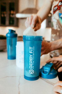 picture of protein being scooped into a protein shaker bottle